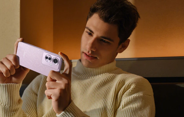 Man shooting a picture with the Coral Purple version of the Oppo Reno11 F 5G