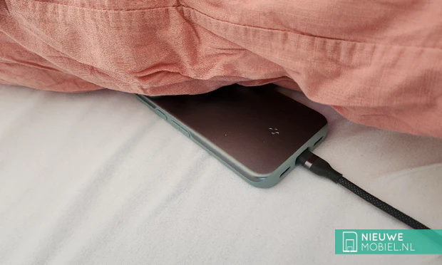 Smartphone bedraad aan de oplader onder een kussen Smartphone bedraad aan de oplader onder een kussen