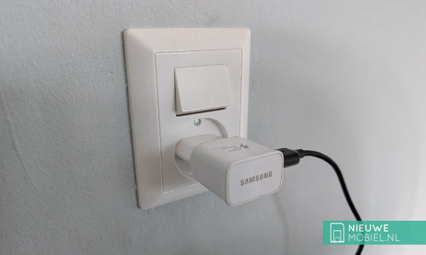 Telefoonoplader in stopcontact Witte Samsung Adaptive Fast Charging muuradapter gestoken in een wit Europees Type-C stopcontact, voorzien van een aangesloten zwarte USB-kabel