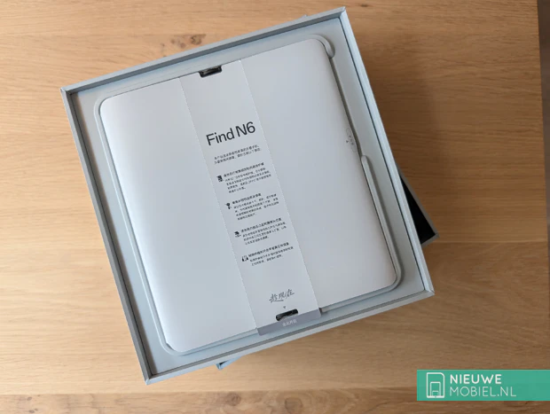 Inhoud van de doos van de Oppo Find N6 De geopende verpakking van de Oppo Find N6 met het toestel in Stellar Titanium, de 80W SuperVOOC-lader en de meegeleverde reisadapter