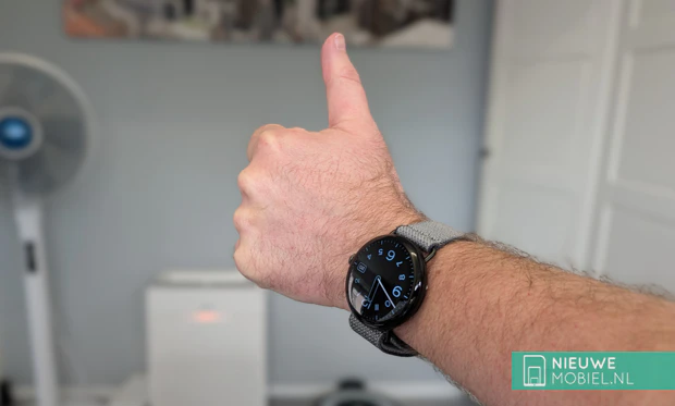 Google Pixel Watch 4 45mm Obsidian zwart met geweven sportband om de pols. Google Pixel Watch 4 in Obsidian zwart om de pols, met duim omhoog
