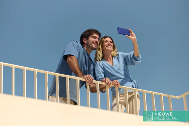 Vrouw maakt vanaf een balkon een foto met de Fairphone Gen. 6+ in Cobalt Blue, naast haar een man