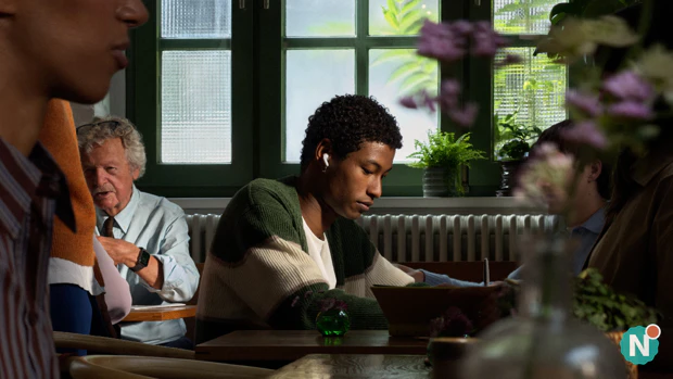 Man zit in druk café met Apple AirPods 5 in
