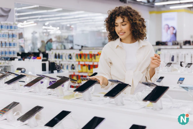 Black Friday-deals op telefoons vergelijken Vrouw vergelijkt verschillende smartphones in een elektronicawinkel